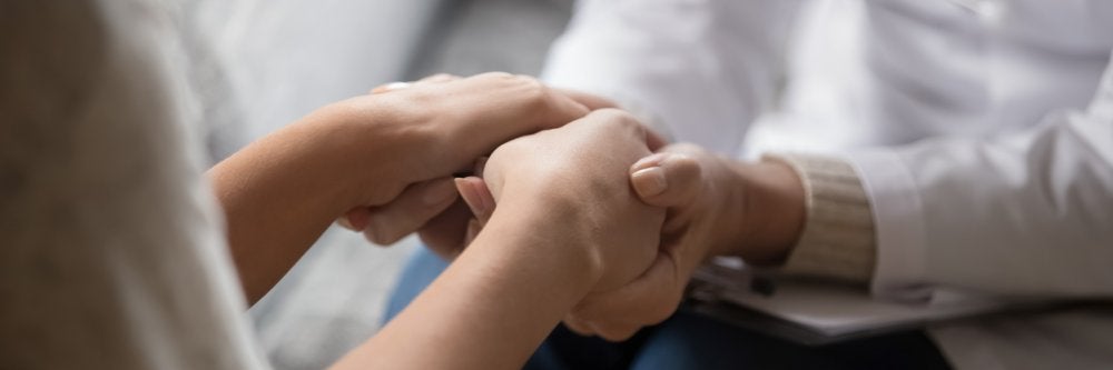 Hand holding hand for comfort and emotional support.