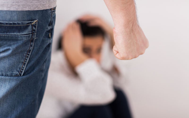 A person in jeans gestures with a raised fist toward someone out of focus in a white shirt.