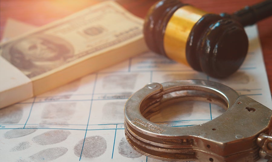 Fingerprint card with handcuffs, a judge's gavel, and a stack of money suggesting legal trouble or bribery.