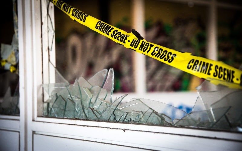 Crime scene tape strung across a broken window