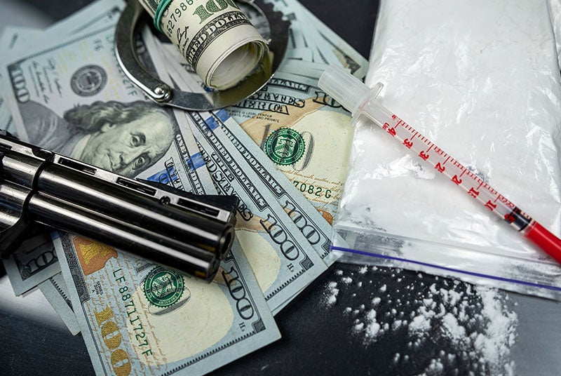 A gavel resting on its block, with various pills and capsules scattered across the block.