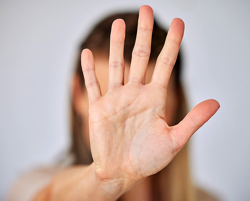 Person holding up a hand with palm facing outward, signaling to stop or no.