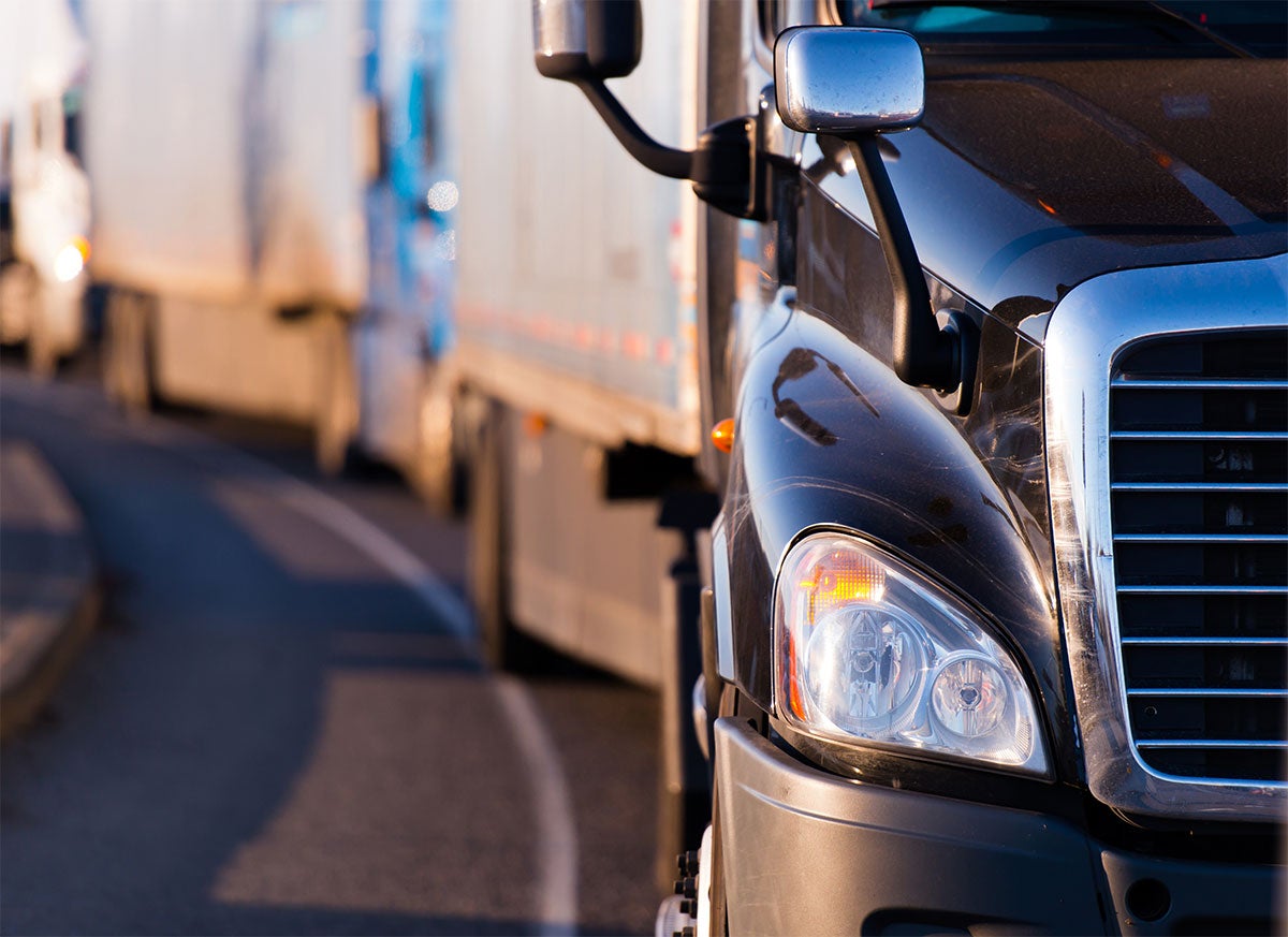 A large semi-truck parked with its front grille and headlight in focus