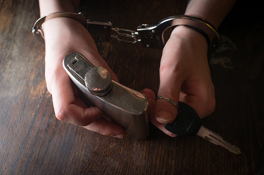 Hands hold a key and handcuffs on a dark wooden surface.